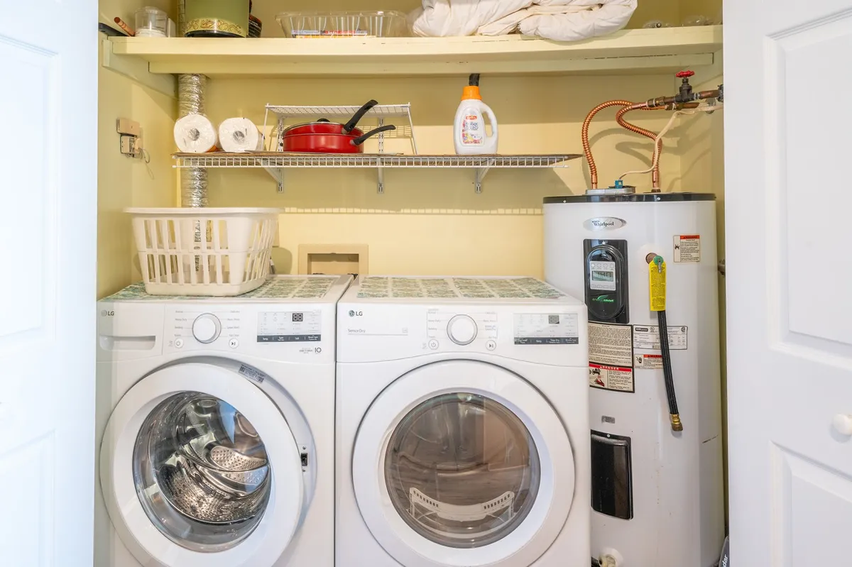 A practical laundry area with a washing machine and dryer, neatly organized with shelves above for household supplies. The setup looks clean, efficient, and easily accessible for guests returning from the beach.