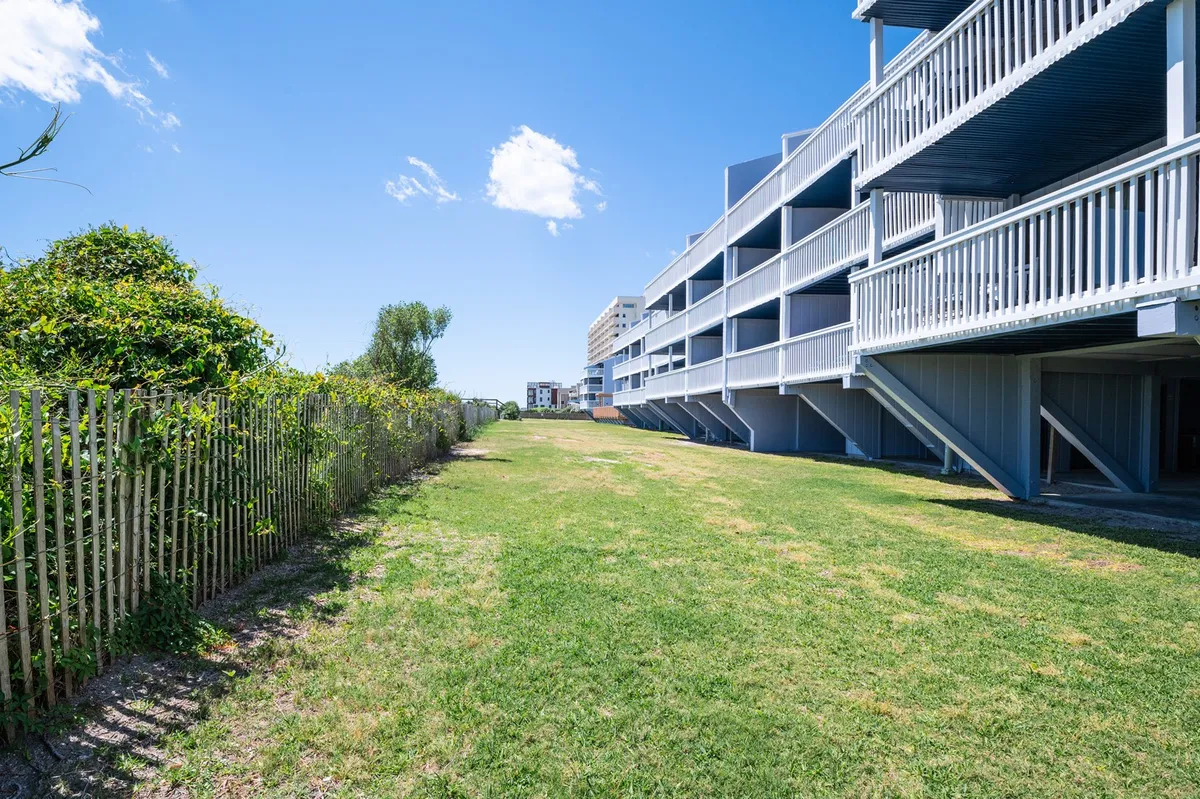 A wide grassy area in front of the building’s balconies, bordered by a fence line. The space is ideal for family picnics, outdoor play, and casual gatherings, with plenty of room to relax and enjoy resort-style lawns.